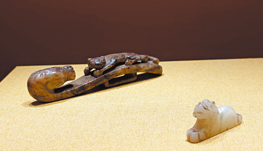 ◆元末明初青玉馬首虎紋帶鈎（左）和遼代白玉虎形飾件。