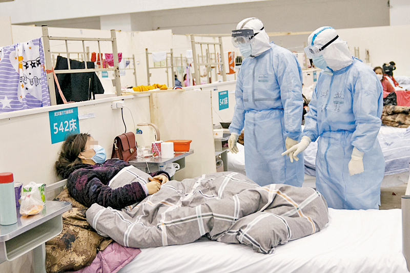 ◆ 2020年2月10日，身穿全身防護服的醫護人員在向患者詢問病情。 資料圖片