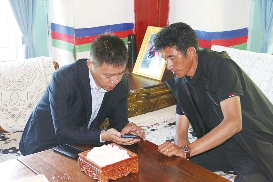 ◆ 農行林芝巴宜區支行員工給嘎啦村村民演示農行興農商城功能。