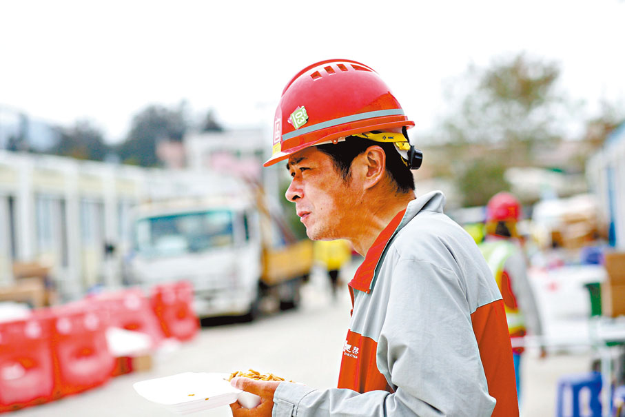 ◆忙碌的工程，虞培忠捧飯盒站在原地開餐，曬黑了的皮膚更見其辛勞。