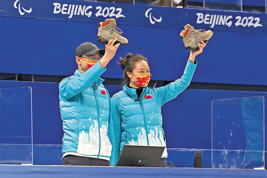 ◆教練岳清爽（右）和李建銳在準決賽後舉起一雙「寶鞋」慶祝勝利。 中新社
