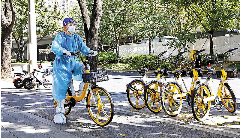 ◆防疫人員騎共享單車出行。 香港文匯報記者郭若溪  攝