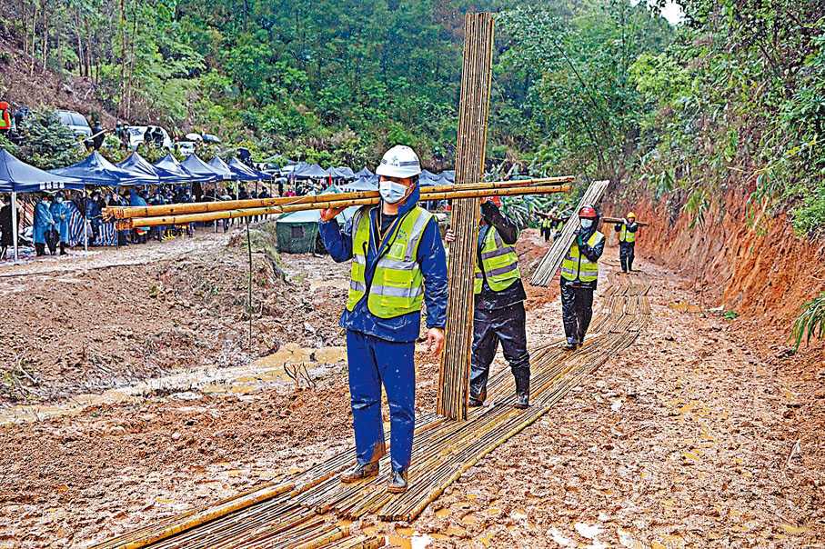 ◆3月23日,墜機事故現場下雨,工作人員在墜機事故現場搬運鋪設道路的竹排。 新華社