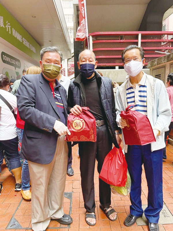 ◆ 香港區潮人聯會監事長張仲哲（左一）和會長胡池（右一）向街坊派發物資。