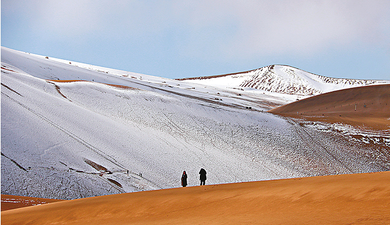 ◆遊客在雪後的鳴沙山月牙泉景區遊覽。