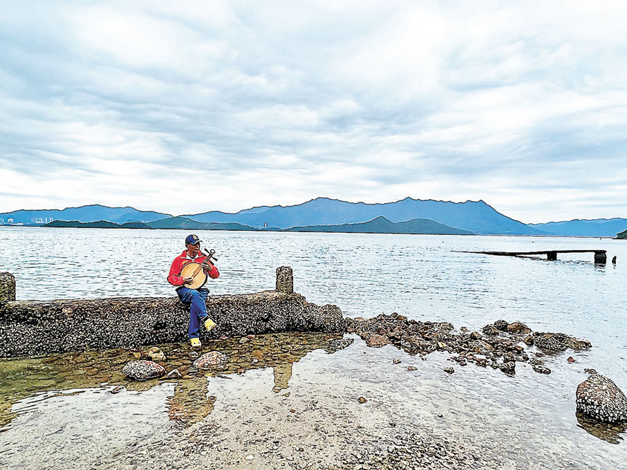 ◆人在海中彈奏港樂，背景是八仙嶺，特別有意思。