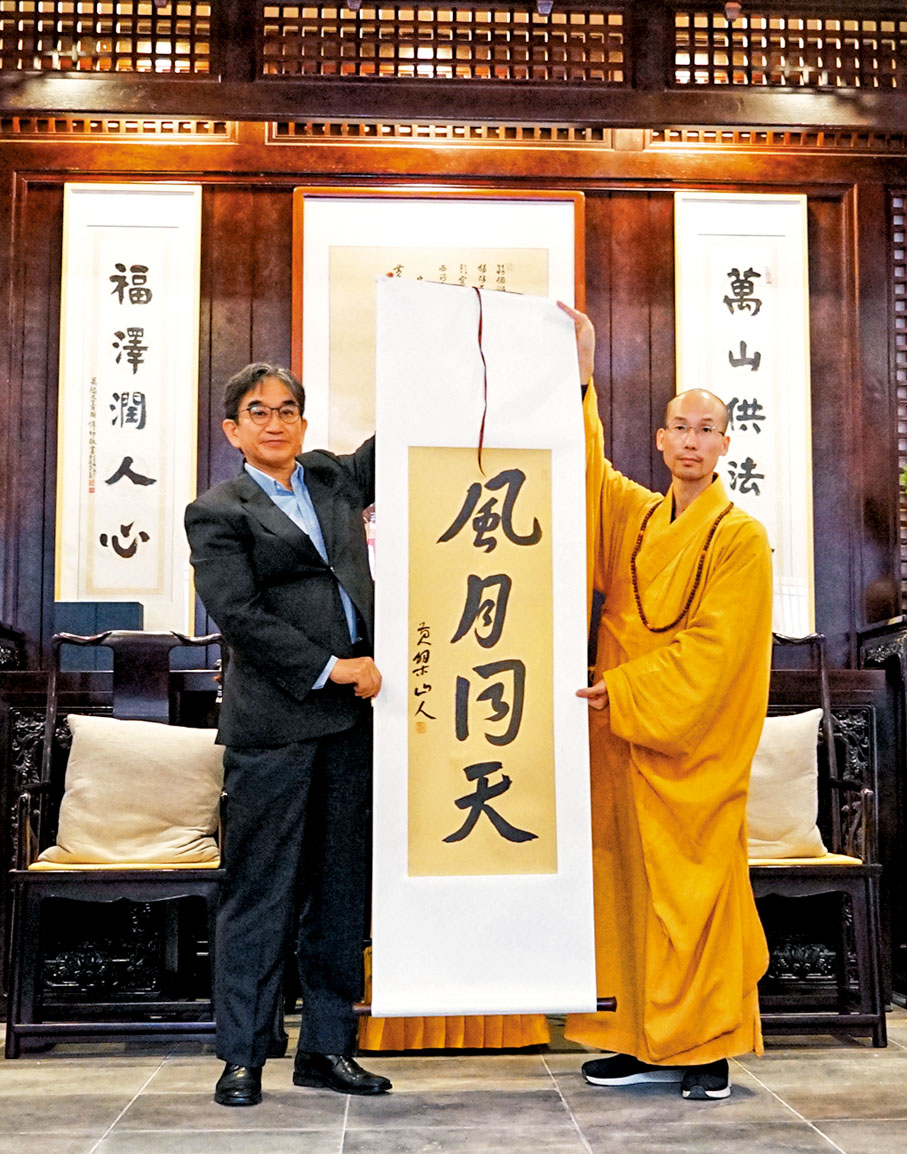 ◆日本駐華大使垂秀夫（左）訪問福建黃檗山萬福寺時獲贈「風月同天」條幅，由福清黃檗山萬福寺方丈定明法師（右）贈送。