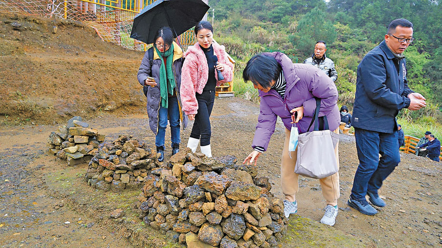 ◆遺址前堆放出土的冶鐵排出物。粉色上衣者為蔡阿虹。