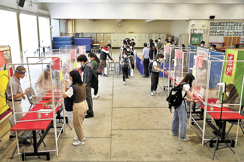 ◆學校於試場外空曠地方設檢查站，讓考生暫除口罩核對身份及准考證。香港文匯報記者  攝