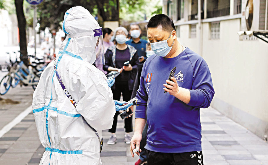 ◆復旦團隊推算模型指，如果放任Omicron不受控傳播，預估在2022年5月至7月，將迎來一波疫情高潮。圖為5月11日，在上海市一個臨時核酸檢測採樣點，工作人員在為市民登記信息。 中通社