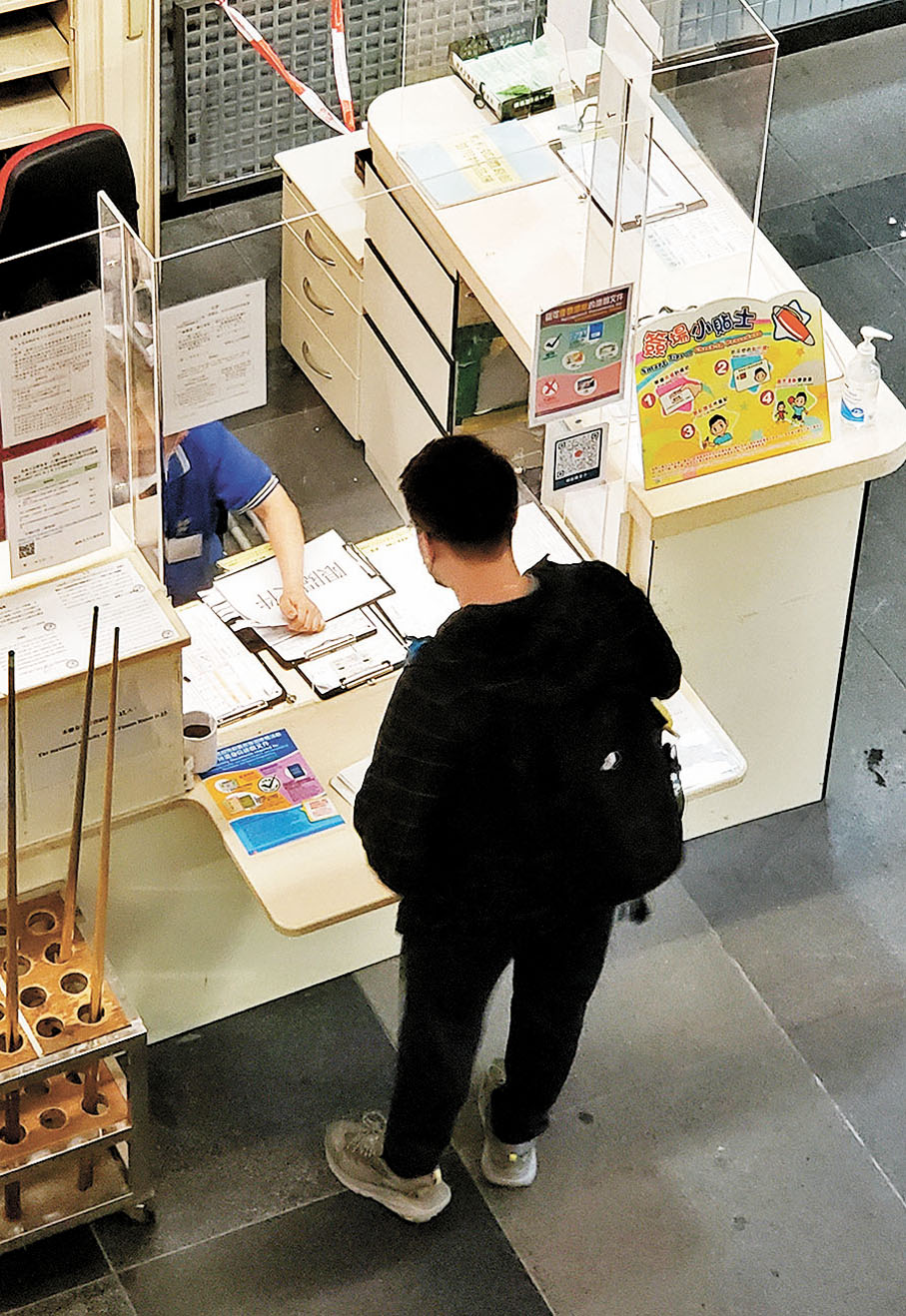 ◆6點50分左右，着黑色格仔衫、灰色登山鞋的男子在登記處簽場。 香港文匯報記者 攝