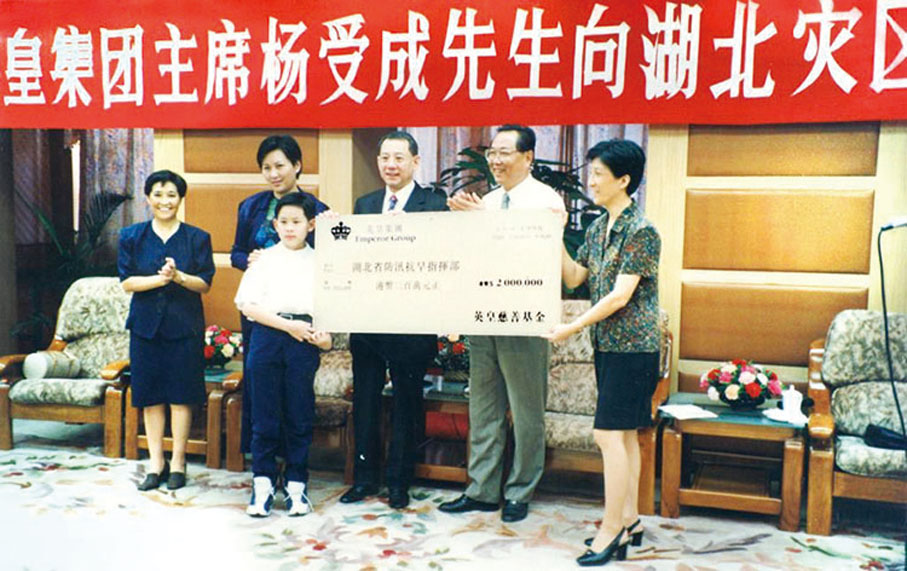 ◆ 楊受成（右三）偕兒子楊政龍在慈善路上並肩而行的事跡可追溯至1998年的湖北水災，當時只有12歲的楊政龍（圖中小童）跟隨父母一同到災區送暖，除捐款以外，望提供更多支援。