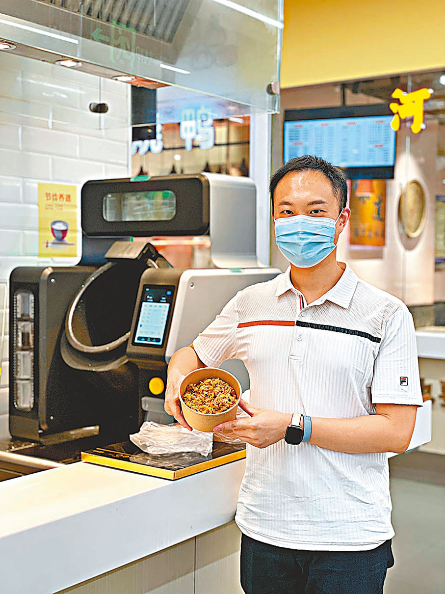 ◆  岑明峰展示身後炒菜機械人做出來的炒飯。  受訪者供圖