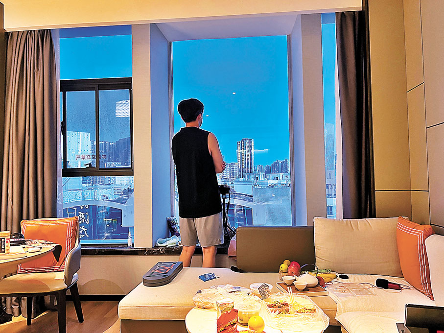 ◆入境隔離新政策公布後，汪女士夫婦備受鼓舞，有望很快解除隔離。圖為汪女士愛人劉先生欣喜地望着酒店窗外。 受訪者供圖