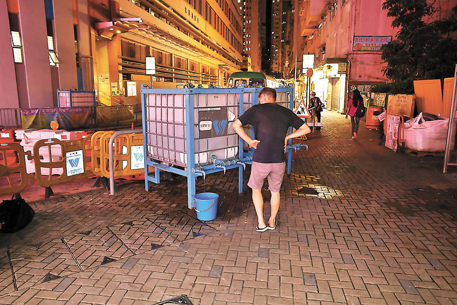 ◆有受爆食水管影響的居民昨晚到樓下臨時水箱取水。香港文匯報記者   攝
