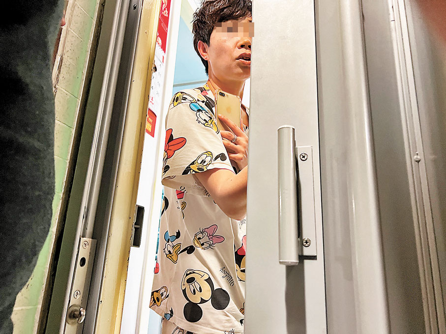 ◆耀東邨耀明樓凶宅單位的住戶隔着鐵閘回答記者簡單提問，強調入住後並沒有發生靈異事件。香港文匯報記者  攝