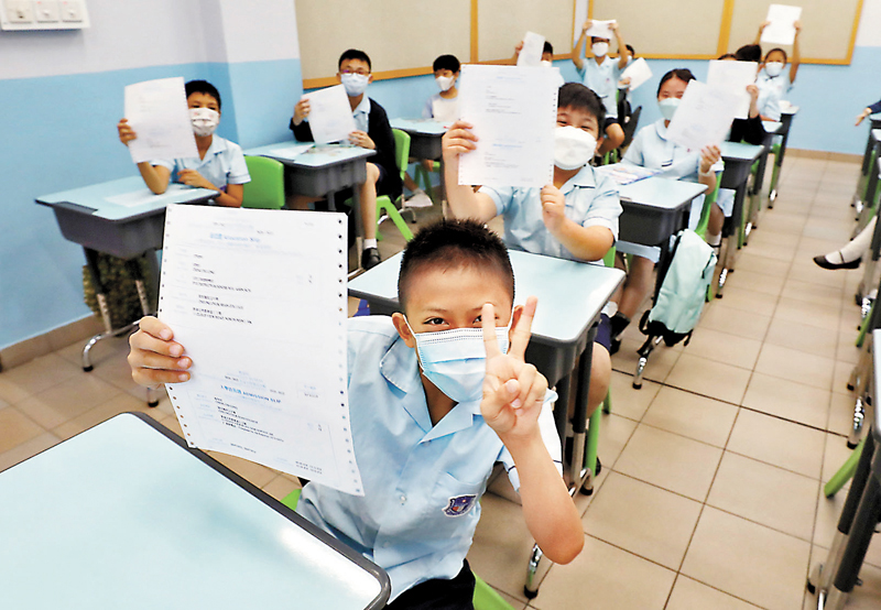 ◆昨日升中派位放榜,香港特區行政長官李家超的小學母校五邑工商總會學校成績十分理想。圖為學生獲派心儀中學興奮展示派位表。