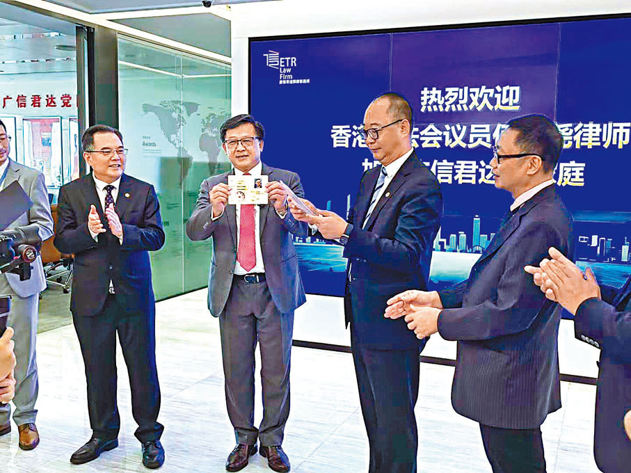 ◆何君堯在律師事務所歡迎儀式上，手持粵港澳大灣區律師執業證。 Fb圖片