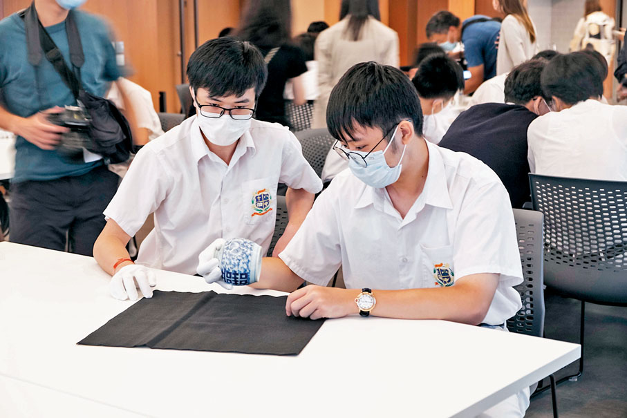 ◆學生拿起清代青花雙「喜」小罐欣賞。香港文匯報記者鄭樂泓  攝