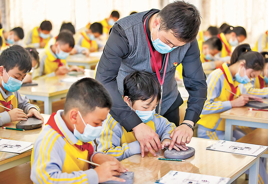 ◆白石村的黃崗小學有一套獨特的端硯校本課程，圖為老師指導學生雕刻端硯。 新華社