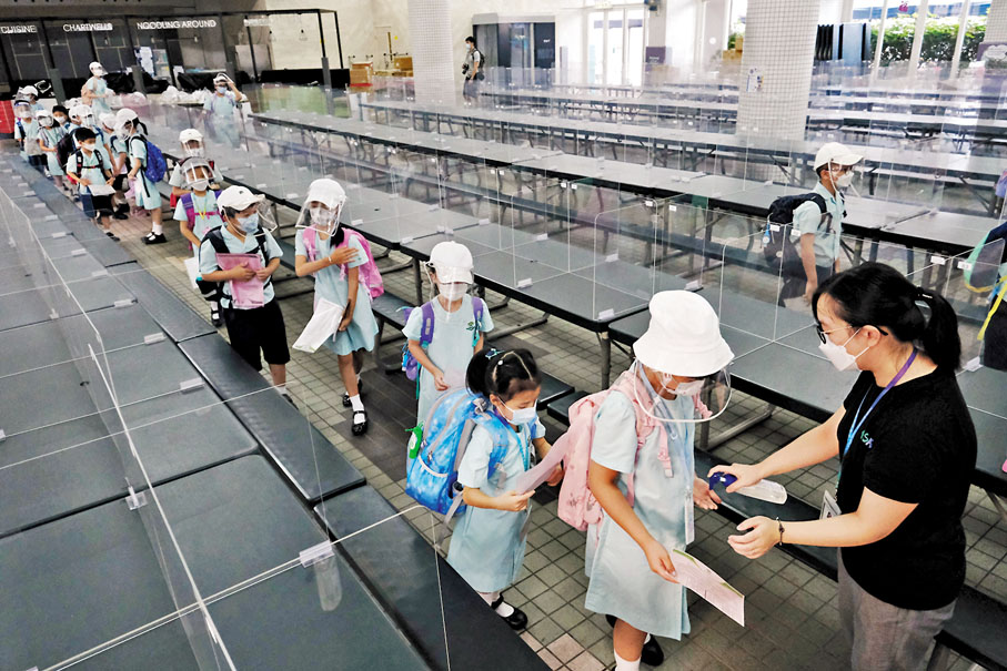 ◆昨日迎來新冠疫情下第三個開學日，有學校教職員檢查學童體溫及快測紀錄表。香港文匯報記者  攝