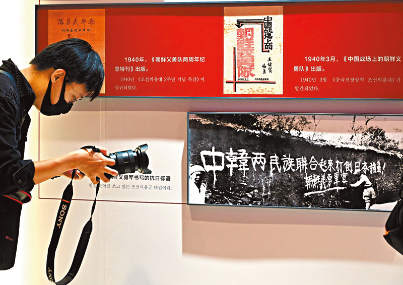 ◆ 中國人民抗日戰爭紀念館舉辦「中韓共同抗戰」專題展覽，一名記者拍攝介紹當年在華朝鮮義勇軍書寫的抗日標語的圖片展板。    中新社