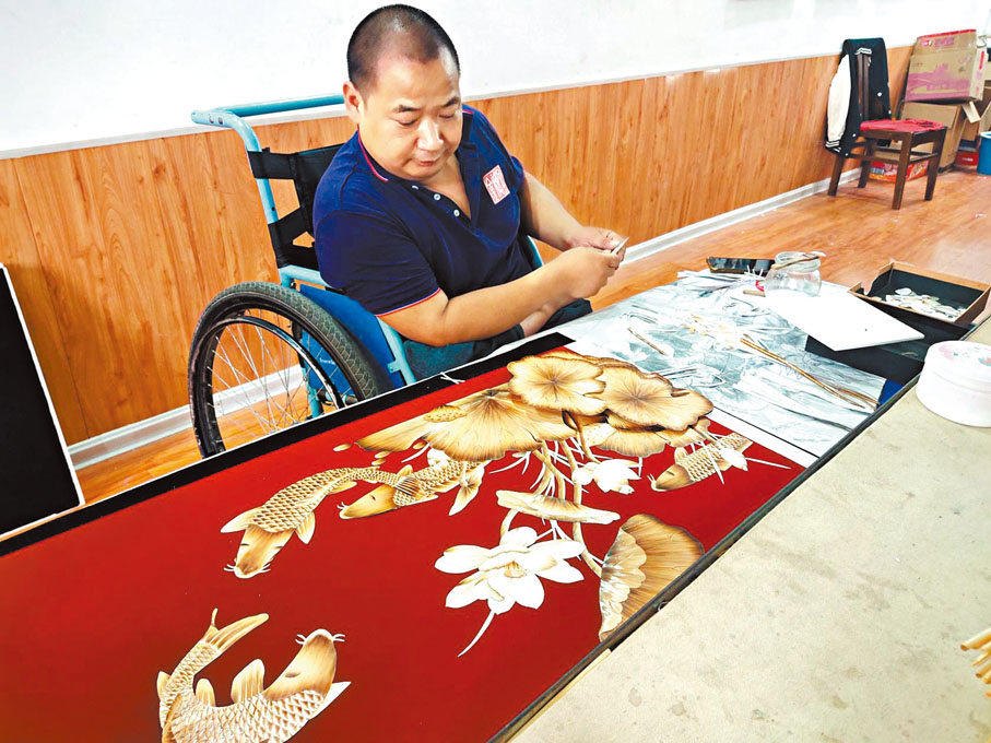 ◆殘疾人潘長江在貼畫。香港文匯報記者戚紅麗 攝