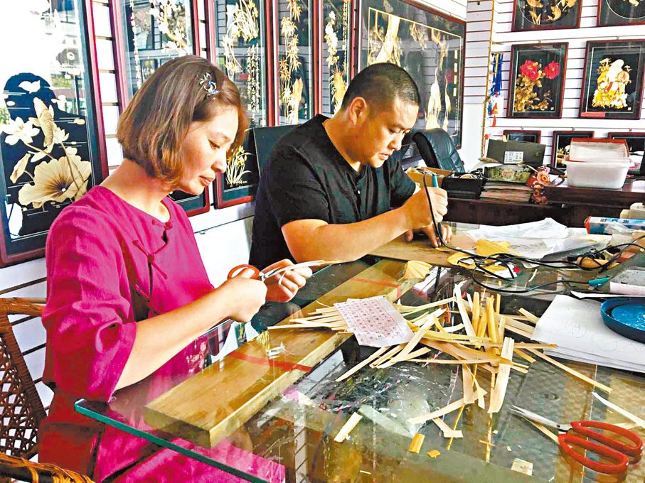 ◆谷穗、葛磊夫婦在製作蘆葦畫。   香港文匯報記者戚紅麗 攝