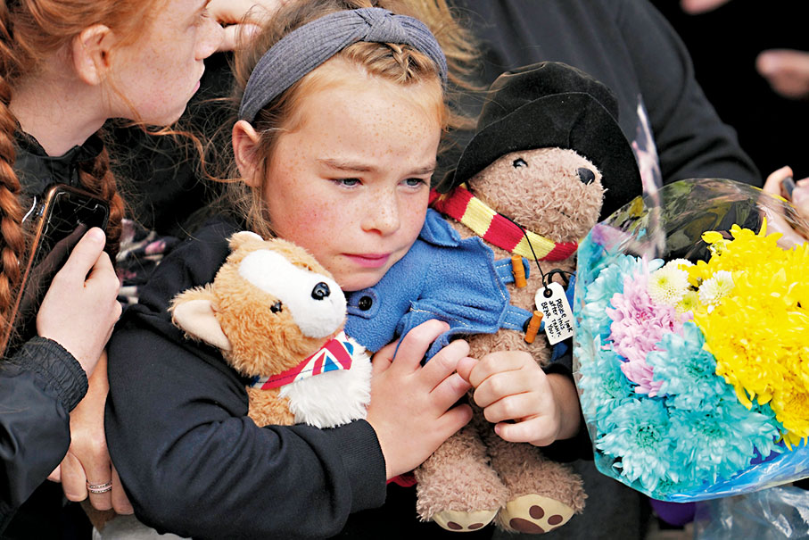 ◆ 愛丁堡女孩手抱小狗和小熊公仔等待見女王最後一面。美聯社