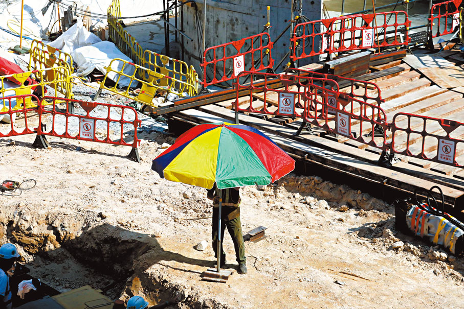 ◆ 戶外工人躲在傘下遮陰。香港文匯報記者  攝