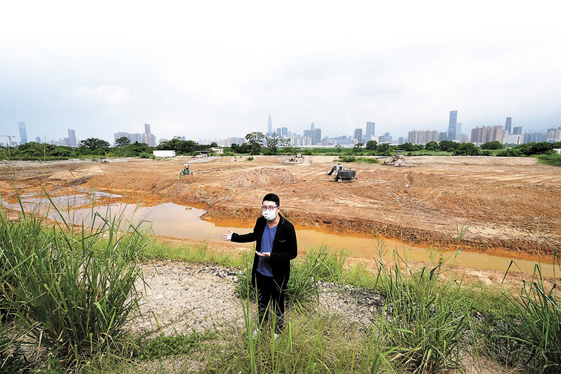 ◆立法會議員劉國勳指向身後一個早已「乾塘」的巨型魚塘，懷疑有人正在違法傾倒泥頭。 香港文匯報記者  攝