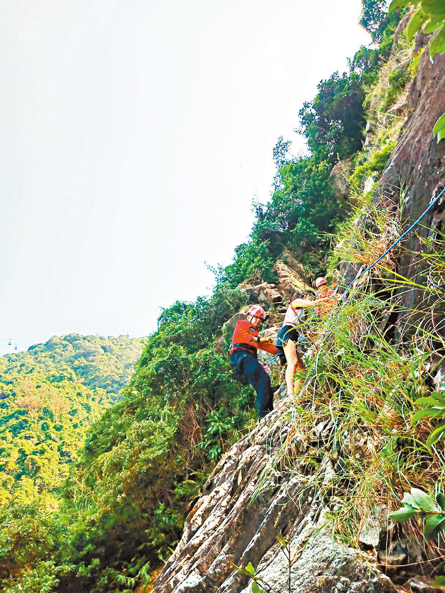 ◆彌䃟石澗摩天崖男子墮崖後，同行友人由民安隊協助救下到安全地方。 民安隊圖片