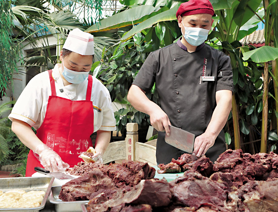 ◆河北省保定市徐水區漕河全驢宴大酒店的兩位師傅正在切驢肉、夾火燒。