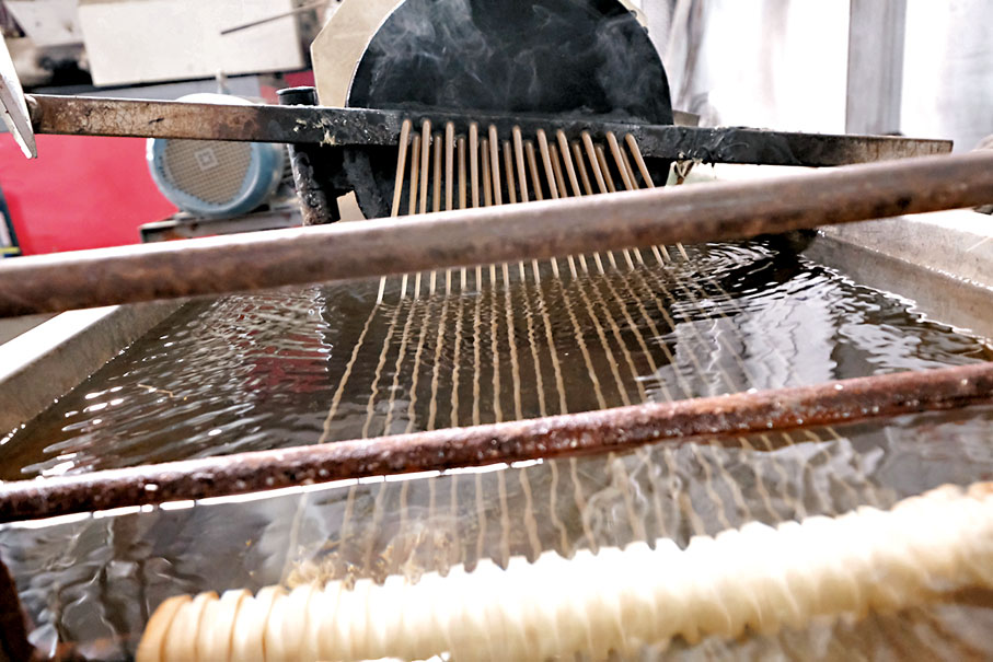 【步驟四】將膠磚放入機器內進行「拉絲」工序及冷卻，再打碎成粒狀膠珠