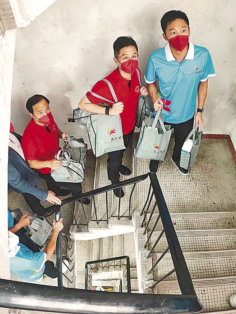 ◆霍啟山（藍衫）與義工身體力行，帶備福袋行樓梯探訪劏房戶。 受訪者供圖