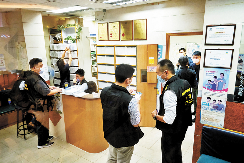 ◆ 警方表示，將全面調查涉持有可疑「免針紙」個案。圖為警方在涉案診所查證。 資料圖片