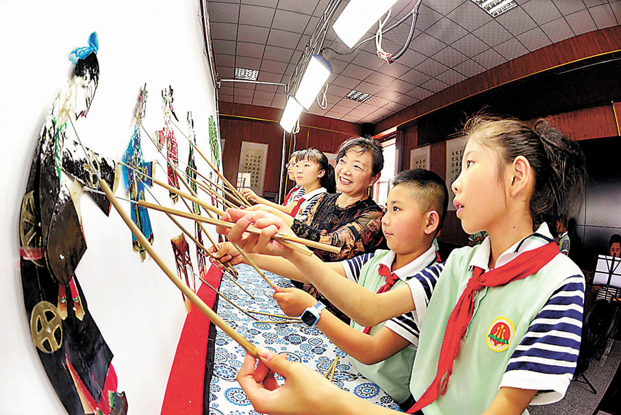 ◆河北樂亭縣的小學生跟隨國家級非物質文化遺產樂亭皮影的表演藝人劉尚傑（中）學習皮影戲表演技藝。 資料圖片