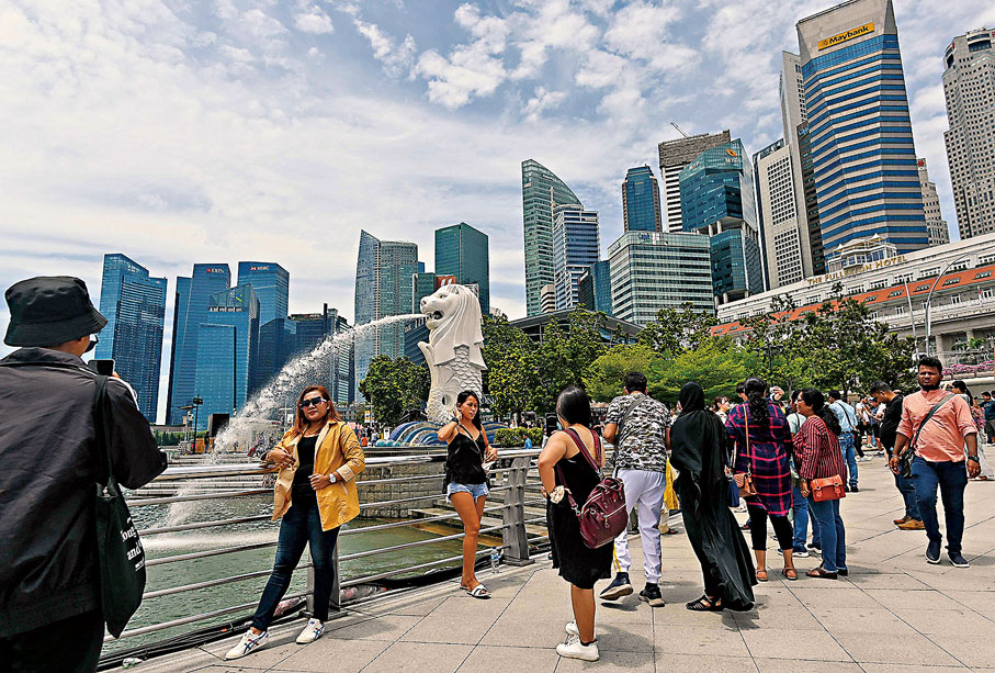 ◆有防疫專家指出，新加坡解除口罩令，以及放寬入境限制，代價是疫情反彈。圖為遊客在魚尾獅公園拍照。資料圖片