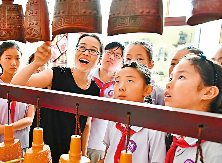 ◆中共二十大報告提出，中國式現代化是物質文明和精神文明相協調的現代化。圖為山東省棗莊市山亭區文化館工作人員在為小學生講解編鐘知識。 資料圖片