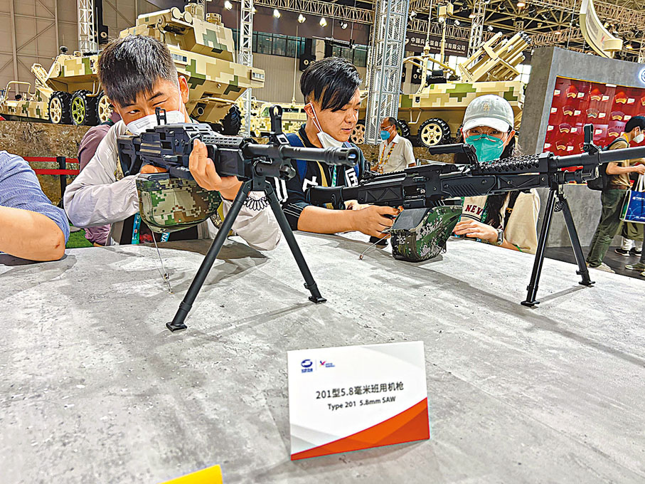 ◆ 中國自主研製的20式新槍族亮相。圖為觀眾（左一）上手把玩201型5.8毫米班用機槍。香港文匯報記者帥誠 攝
