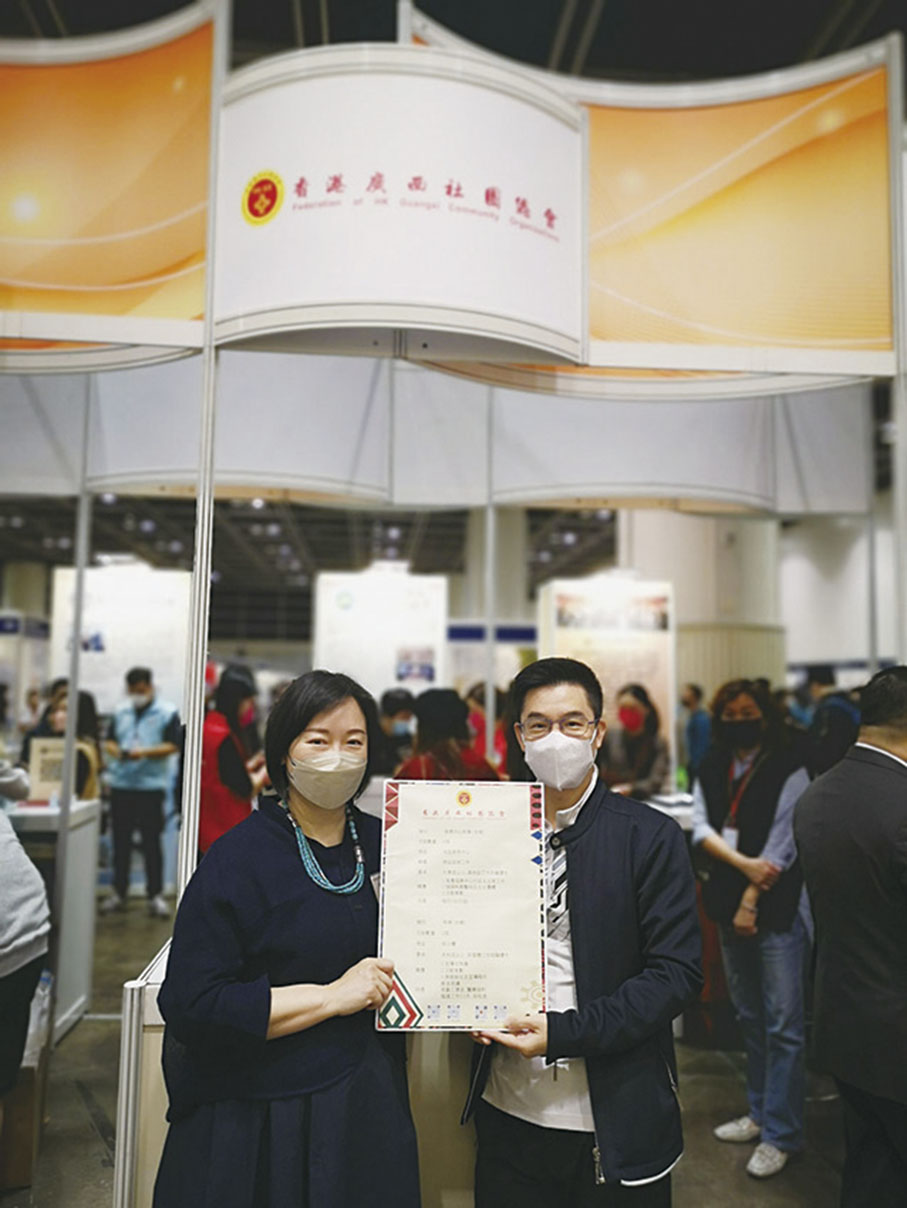 ◆ 香港廣西社團總會會長文頴怡（左）在展區前展示廣西社團資料。
