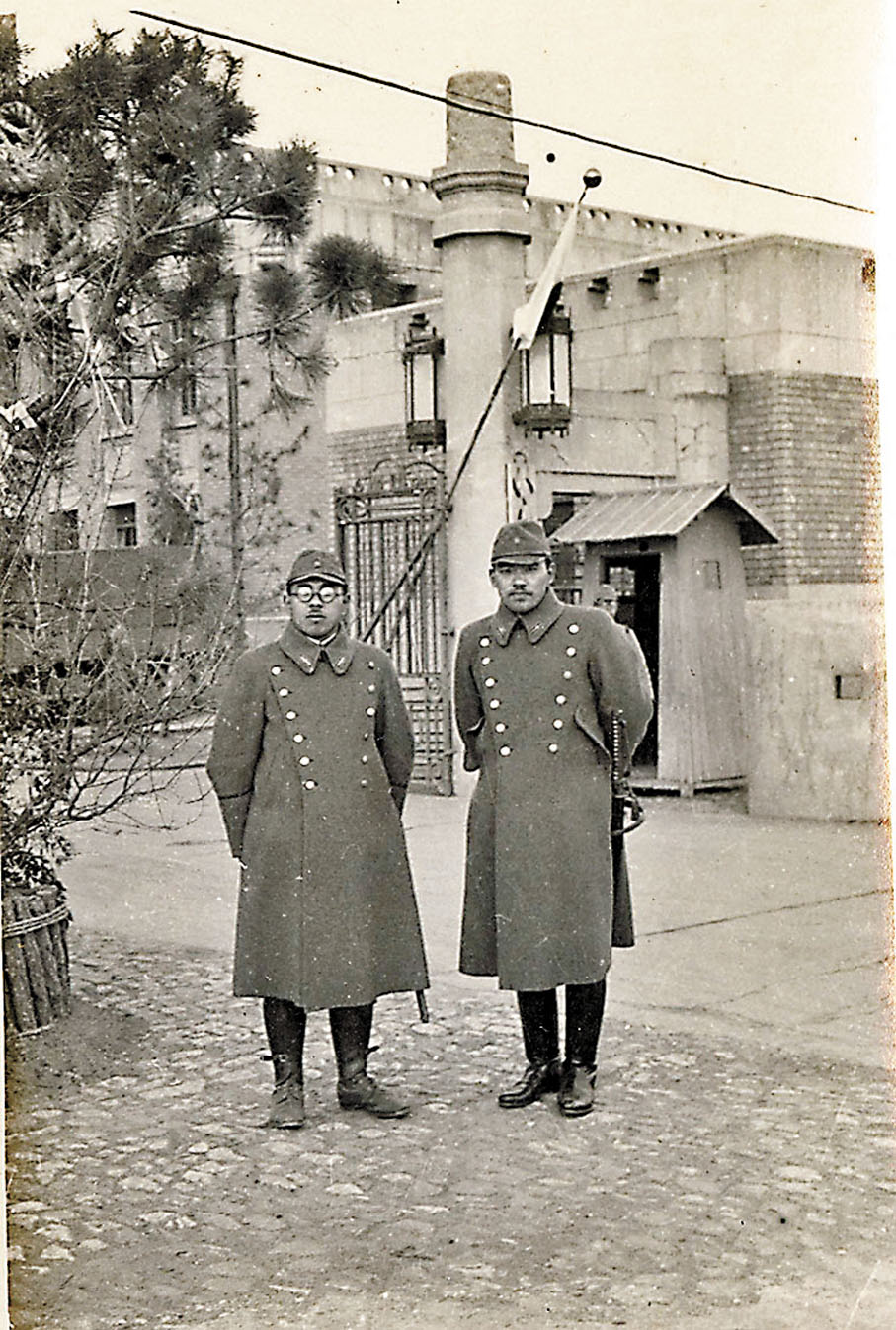 ◆兩名佩戴刺刀的日本兵，站在「榮第1644部隊」總部大門前合影。受訪者供圖