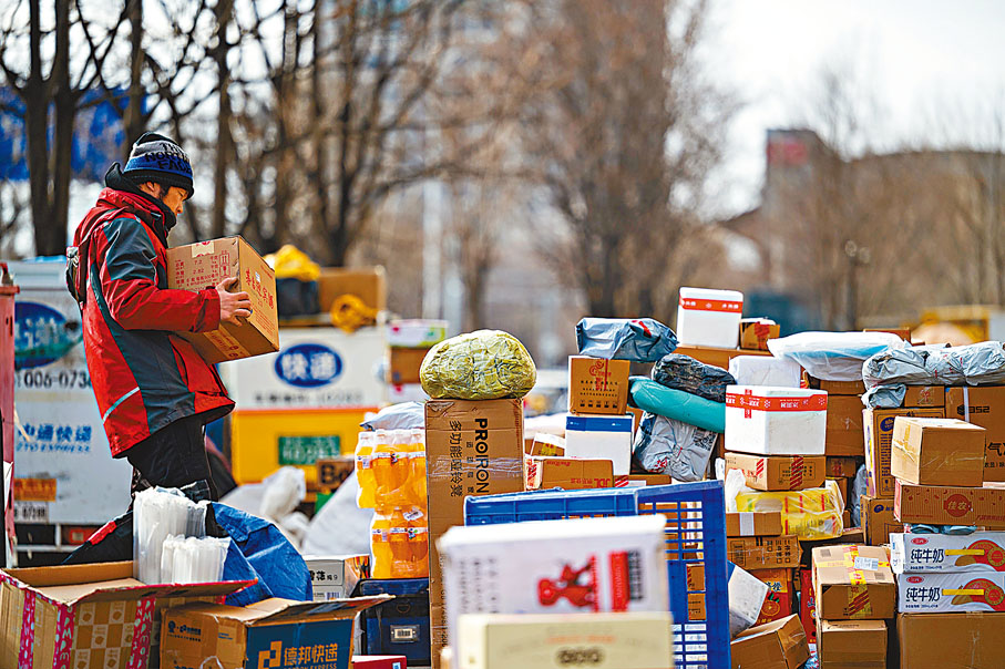◆12月15日，北京市一居民小區外，快遞派送員正在整理清點快件，準備為居民派送。   中新社