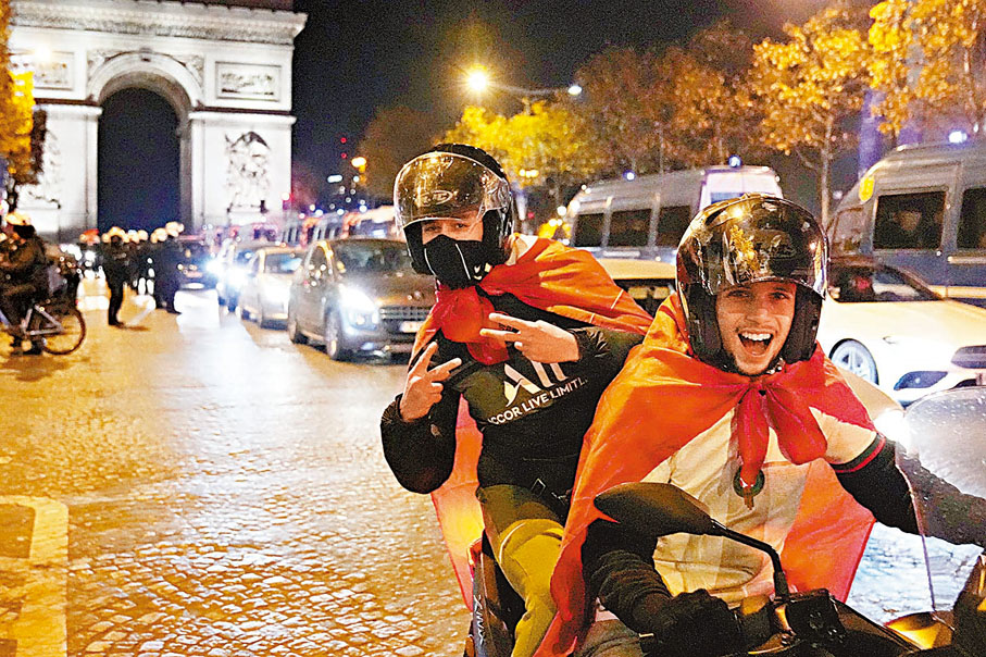 ◆兩名青年身披摩洛哥國旗，在香榭大道慶祝。 美聯社