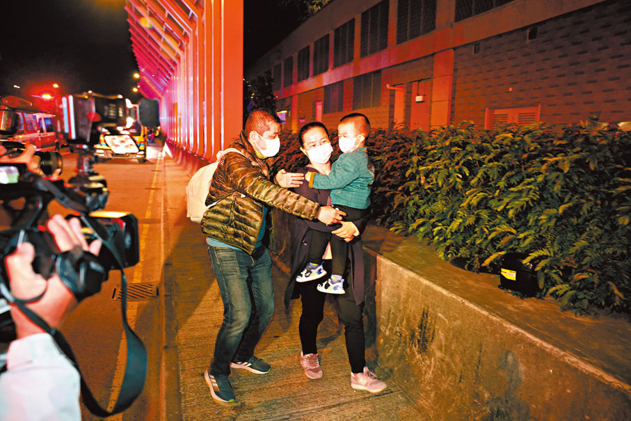 ◆一名獲救男童懷疑受驚，由家人抱離現場。香港文匯報記者鄺福強  攝