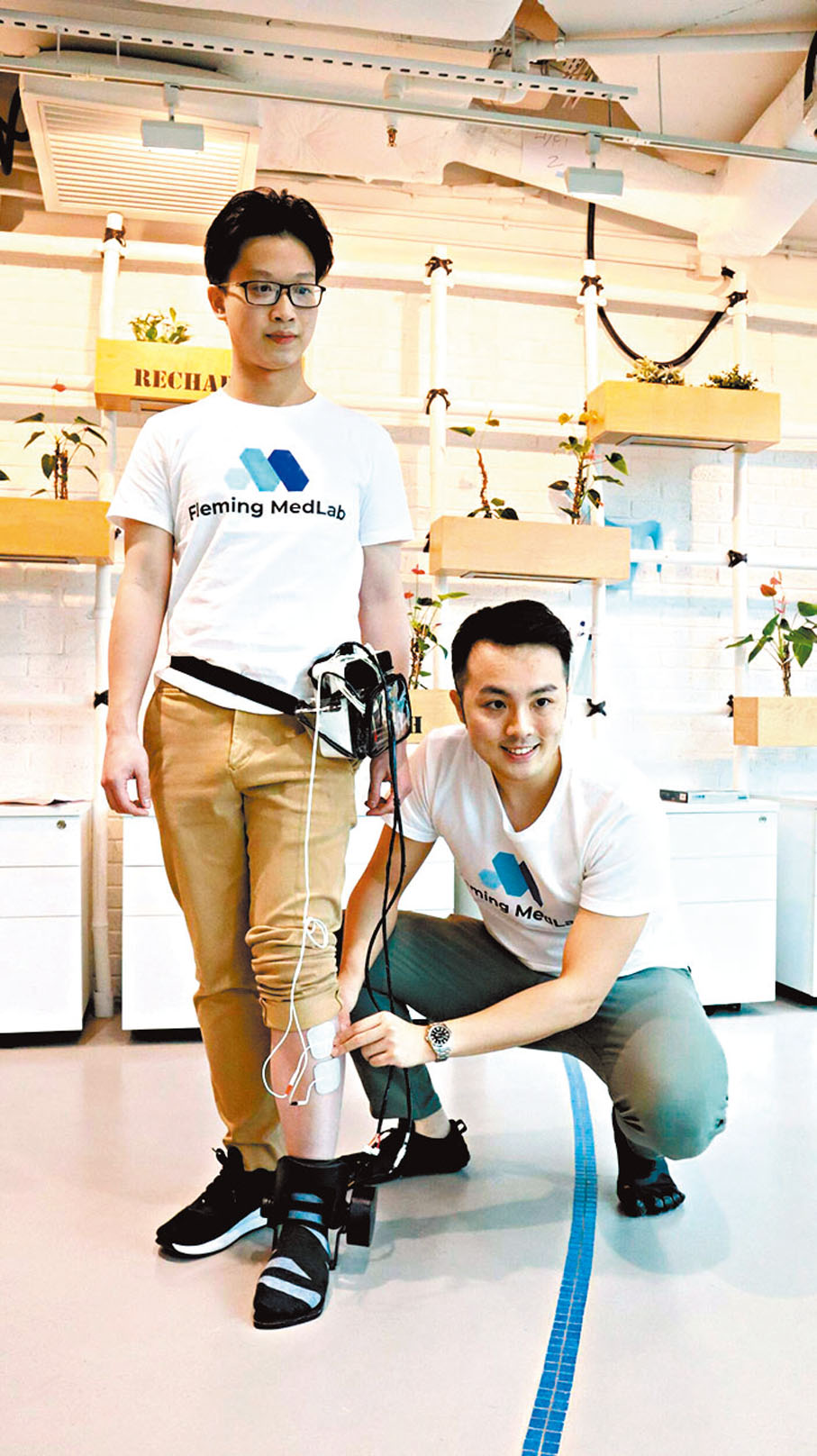◆鄭栢誠（右）與香皓林示範由他們研發的醫療級穿戴式機器人「Fleming腳托」。