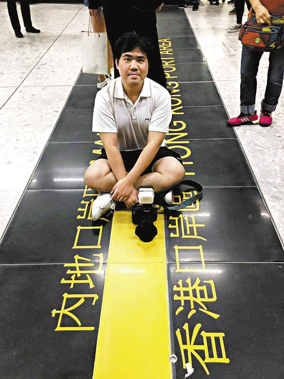 ◆ 2018年9月23日，黃文偉坐在香港西九龍站內的口岸分隔線上留影。   受訪者供圖