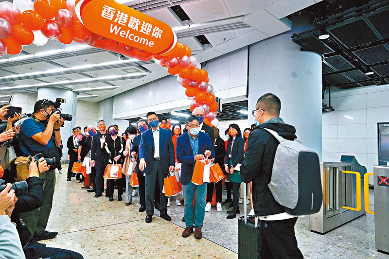 ◆林世雄、楊潤雄聯同港鐵高層在站內迎接抵港乘客，向他們送上紀念品。香港文匯報記者曾興偉 攝