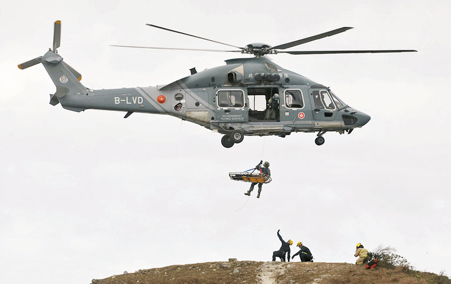 ◆消防處攀山拯救專隊隊員拯救傷者，由飛行服務隊用直升機吊運傷者送院。 香港文匯報記者郭木又  攝