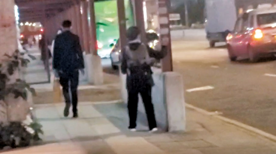 ◆2月14日晚，李盈姿（右一）在多處的牆壁、水柱、燈柱、燈杆上貼街招。讀者供圖